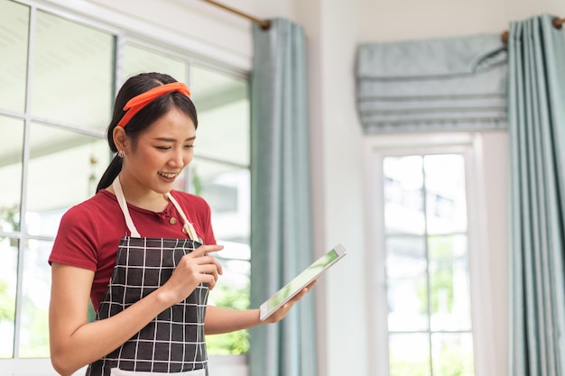 Donna asiatica che usa un tablet per cucinare nella sua cucina