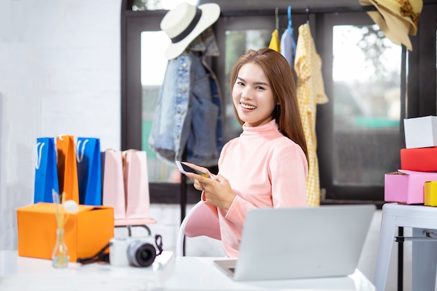 Donna asiatica che utilizza computer e che sorride mentre sedendosi nell'officina