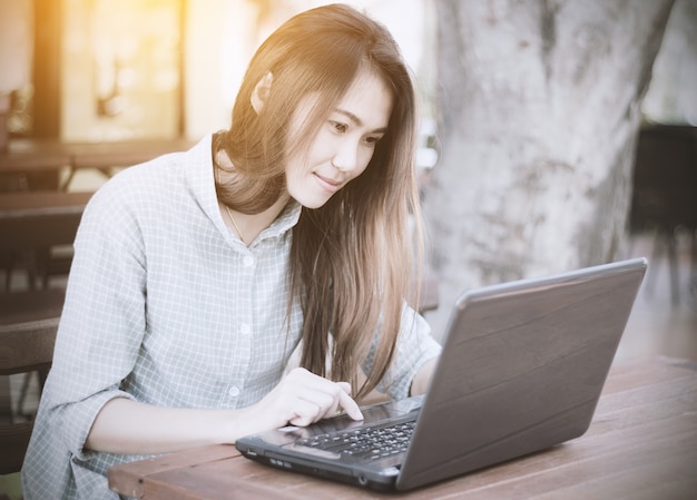 Donna asiatica che utilizza computer portatile alla caffetteria