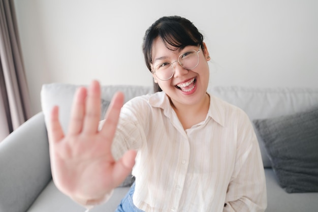 Donna asiatica che utilizza lo smartphone per la videoconferenza con gli amici che agitano la mano facendo un gesto di saluto