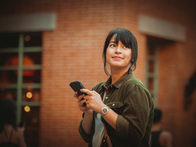 Donna asiatica che utilizza smartphone con umore felice nel centro commerciale