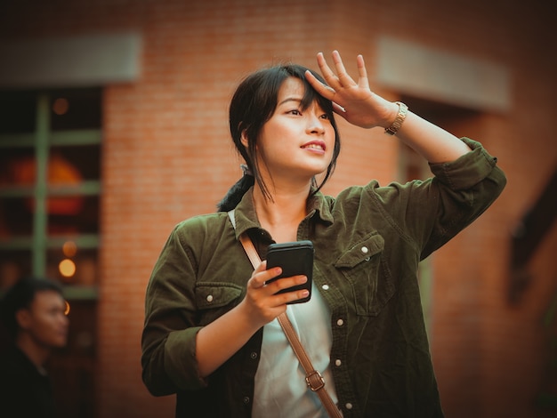 Donna asiatica che utilizza smartphone con umore felice nel centro commerciale