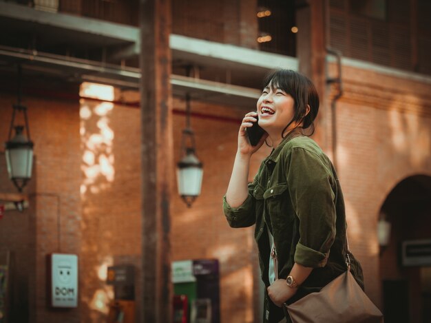 Donna asiatica che utilizza smartphone con umore felice nel centro commerciale