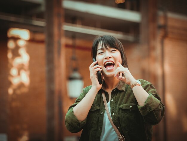 Donna asiatica che utilizza smartphone con umore felice nel centro commerciale