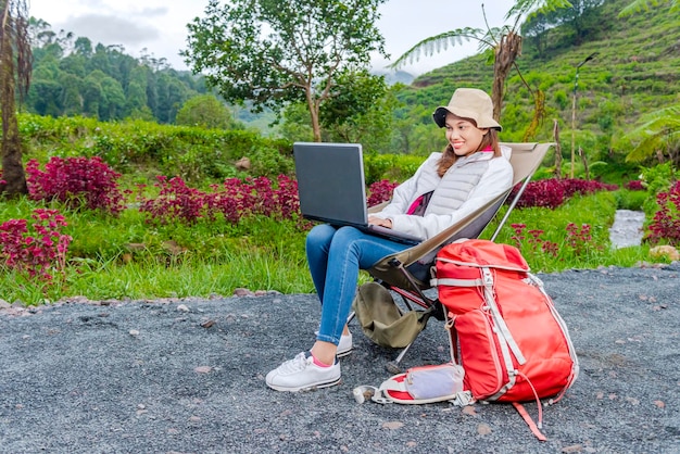 Donna asiatica che utilizza un computer portatile mentre si gode l'attività del campo