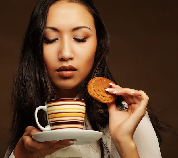 Donna asiatica con caffè e biscotti.