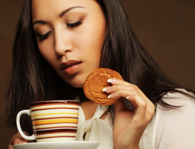 Donna asiatica con caffè e biscotti.