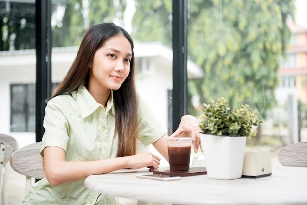 Donna asiatica con caffè sul tavolo seduto nella caffetteria