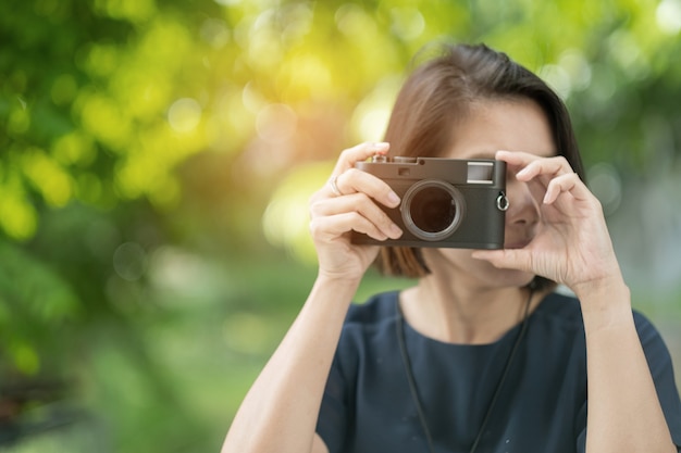 Donna asiatica con in mano una macchina fotografica, fotografo professionista