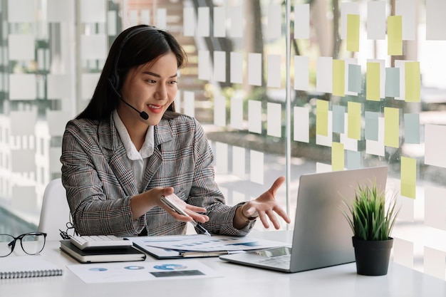 Donna asiatica con indosso le cuffie che si diverte a guardare il webinar educativo sul laptop Giovane uomo d'affari di razza mista sorridente che tiene una videochiamata con i partner dei clienti