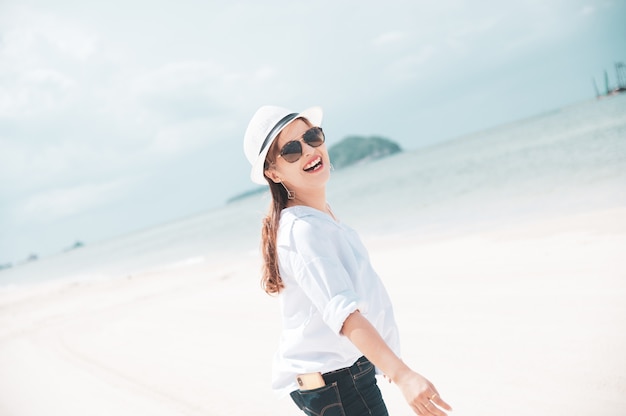 Donna asiatica con la camicia bianca che si distende sulla spiaggia, ora legale