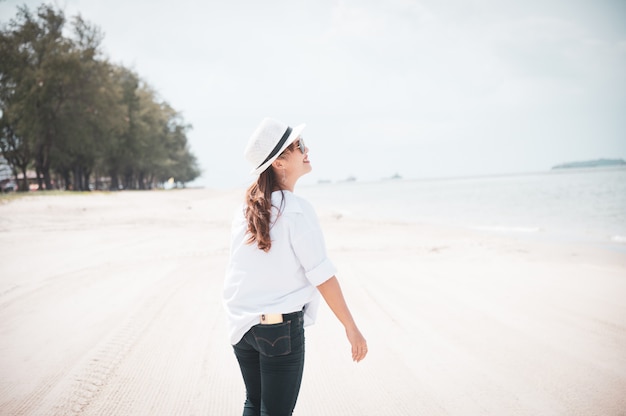 Donna asiatica con la camicia bianca che si distende sulla spiaggia, ora legale