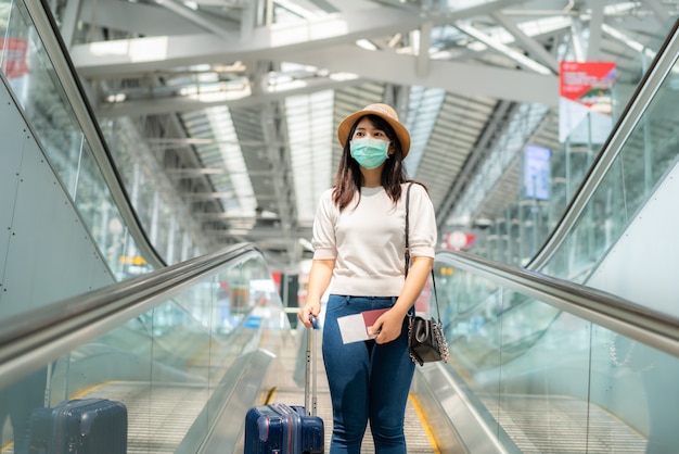 Donna asiatica con la maschera da portare dei bagagli