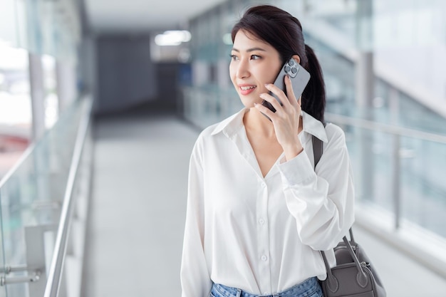 Donna asiatica con smartphone che cammina sullo sfondo di un edificio sfocato strada Affari di moda