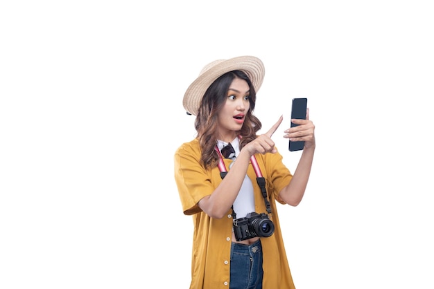 Donna asiatica con un cappello e una macchina fotografica utilizzando un telefono cellulare