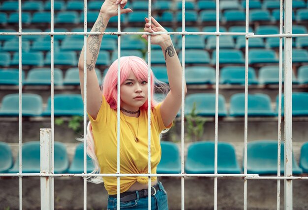 Donna asiatica dai capelli rosa che tiene sulla rete fissa