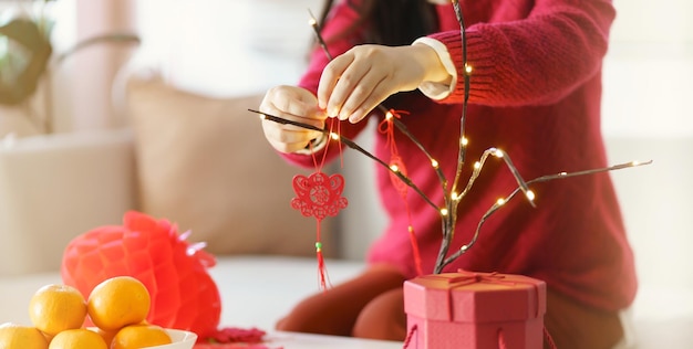 Donna asiatica decorata casa per le celebrazioni del Capodanno cinese mettendo il tradizionale ciondolo al Capodanno lunare cinese per buona fortuna La parola cinese significa benedizione