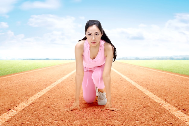 Donna asiatica del corridore pronta a correre sulla pista corrente