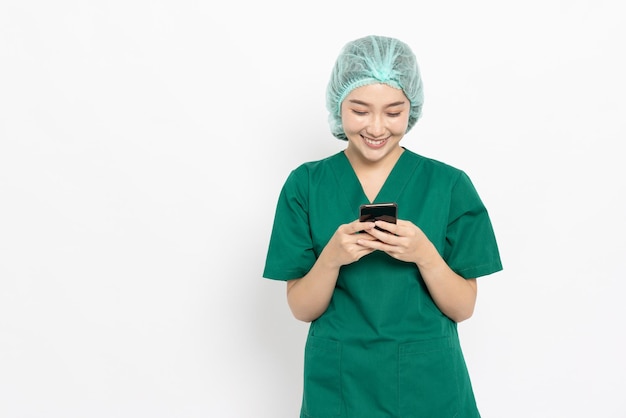 Donna asiatica del medico o dell'infermiera che utilizza il telefono cellulare isolato sopra priorità bassa bianca