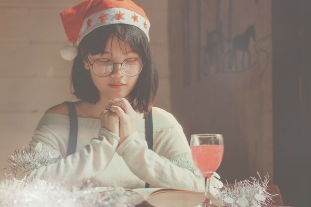 donna asiatica del primo piano, libro di lettura del cappello di Natale di usura teenager della ragazza con felice.