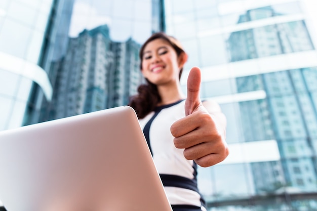 Donna asiatica di affari che lavora fuori sul computer