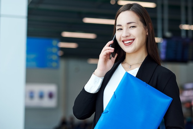 Donna asiatica di affari che parla sul telefono. Ritratto di una bella ragazza in ufficio o sala riunioni