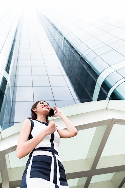 Donna asiatica di affari che telefona fuori con il telefono