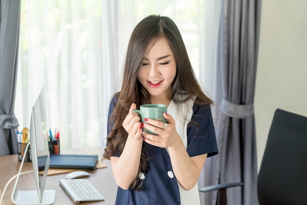 donna asiatica di affari felice con la tazza di caffè