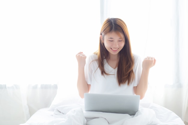 Donna asiatica di bella felicità che usando lavoro del computer portatile