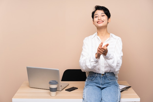 Donna asiatica di giovani affari nel suo applaudire sul posto di lavoro