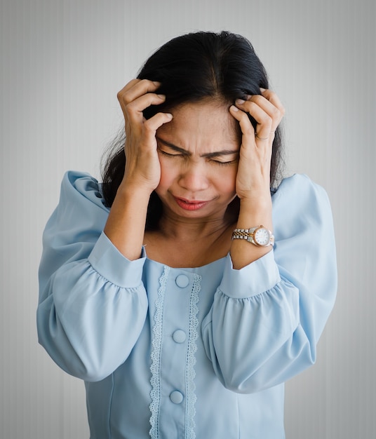 Donna asiatica di mezza età che sente dolore e soffre di mal di testa improvviso e attacco di ictus cerebrale e tiene la testa con la faccia sofferente. Concetto di cervello e problema alla testa.