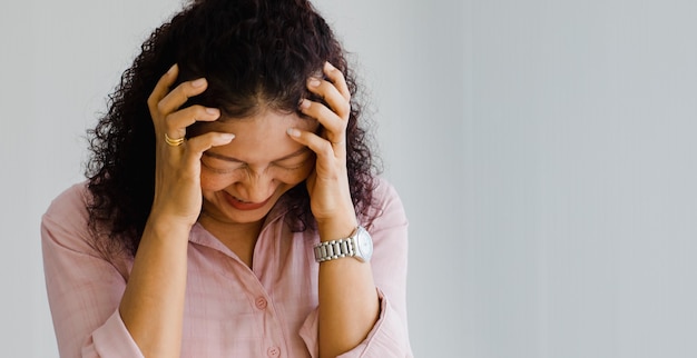 Donna asiatica di mezza età che sente dolore e soffre di un improvviso attacco di ictus e tiene la testa con la faccia sofferente. Concetto di cervello e problema alla testa.