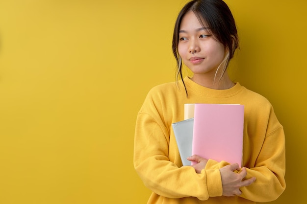 Donna asiatica diligente del ritratto che abbraccia libri che legge l'istruzione studiando l'apprendimento