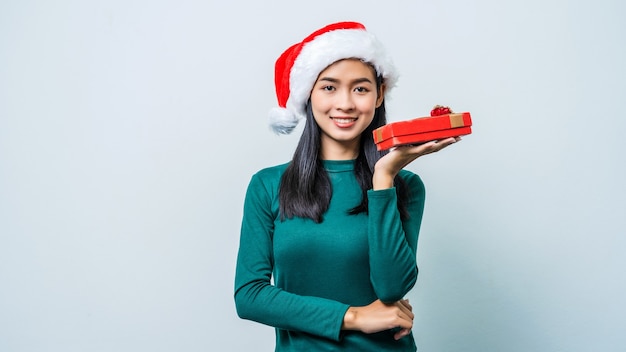 Donna asiatica emozionante felice con il contenitore di regalo della tenuta del cappello di Babbo Natale per la stagione di natale.