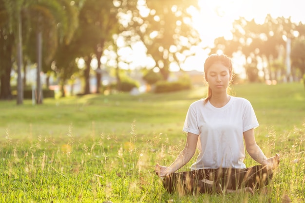 Donna asiatica facendo esercizi di yoga nel parco