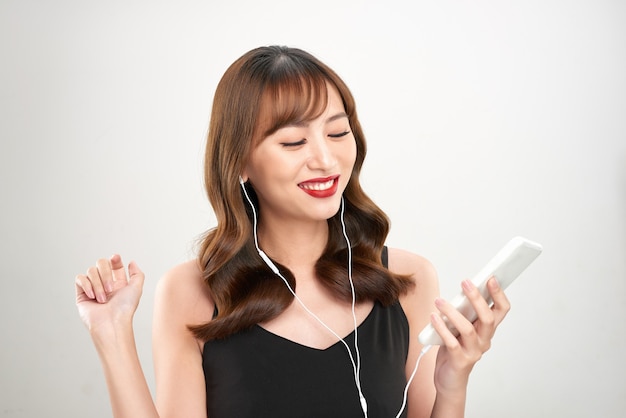 Donna asiatica felice che ascolta la musica sulle cuffie. Modello femminile asiatico fresco giovane