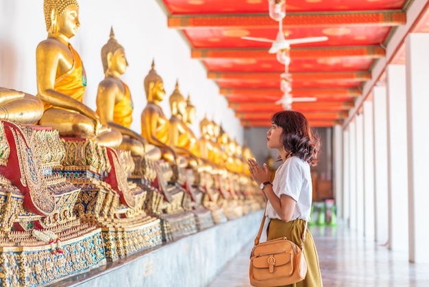 Donna asiatica felice che prega con Buddha