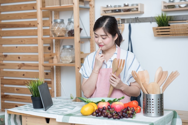 Donna asiatica felice che produce ricetta nella cucina