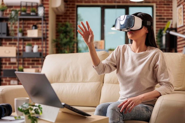 Donna asiatica felice che si diverte indossando la cuffia per realtà virtuale VR, la moderna tecnologia degli occhiali per la simulazione del gioco di intrattenimento digitale del gadget del dispositivo futuro
