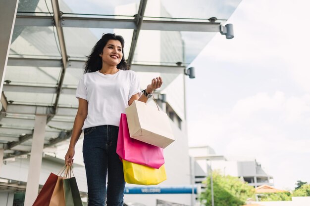 donna asiatica felice che tiene le borse della spesa nel concetto di stile di vita del centro commerciale