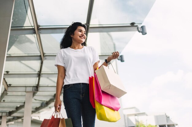 donna asiatica felice che tiene le borse della spesa nel concetto di stile di vita del centro commerciale