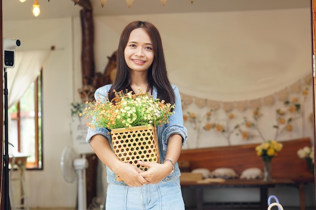 Donna asiatica felice che tiene una caffetteria che tiene fiori