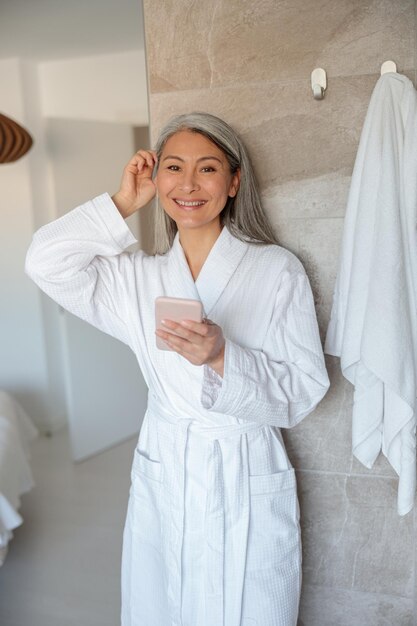Donna asiatica felice con lo smartphone in bagno