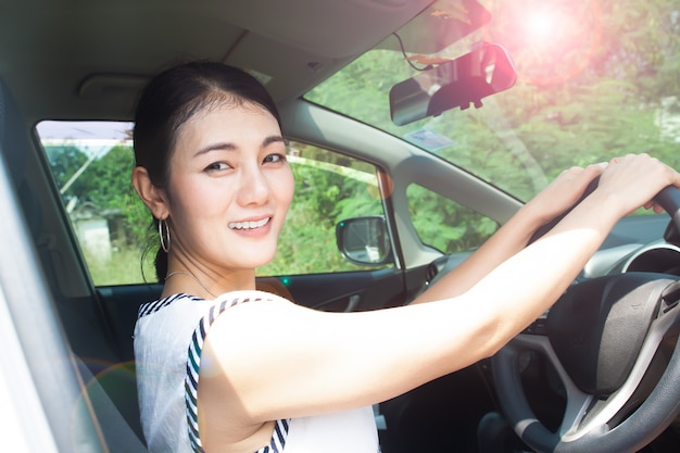 Donna asiatica guida auto, giornata di sole. Protezione UV o concetto di cura della pelle