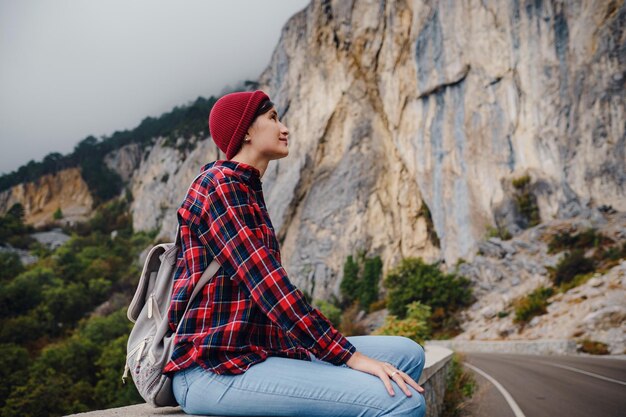 Donna asiatica hipster che cammina da sola su un'autostrada di montagna in una giornata nebbiosa autunnale