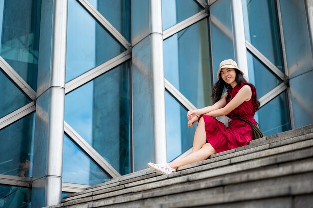 Donna asiatica in abito rosso in edificio moderno, ragazza femminile con lo stile di vita urbano della città