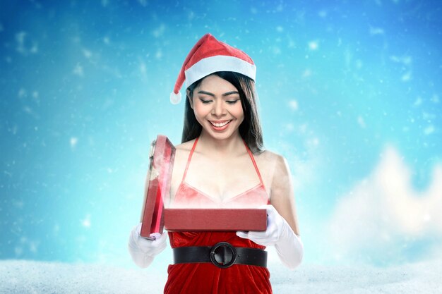 Donna asiatica in costume di Santa che apre il contenitore di regalo