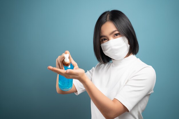 Donna asiatica in maschera per il viso lavarsi le mani utilizzando gel igienizzante per le mani per lavare per evitare il virus