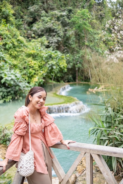 Donna asiatica in piedi sulla passerella di legno nella cascata di Kuang Si Lung Prabang Laos