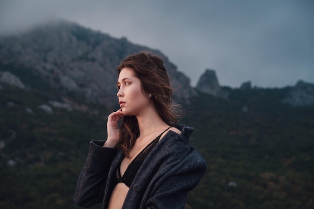 Donna asiatica in un cappotto grigio che gode della vista sulle montagne